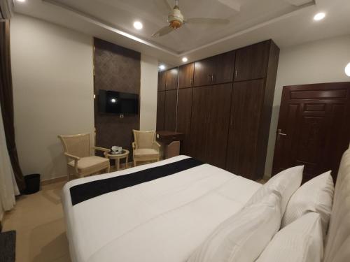 a bedroom with a bed and a tv and chairs at Aspire Lodge, G11 Islamabad - A Family Guest House & Hotel in Islamabad