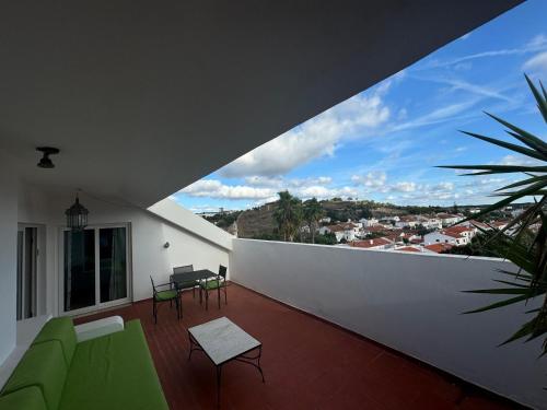 a balcony with green chairs and a white wall at Pateo dos Solares Charm Hotel in Estremoz