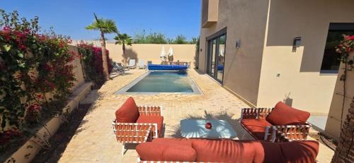 a patio with chairs and a pool in a building at Villa Saadia in Douar Bellouk