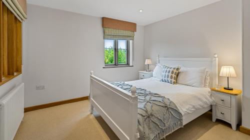 a white bedroom with a bed and a window at Mercia House in Winchcombe