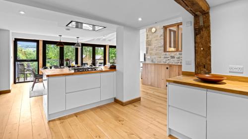 an open kitchen with white cabinets and wood floors at Mercia House in Winchcombe