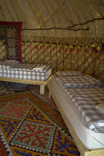 two beds in a yurt with rugs at Yurt camp Sonun in Bokonbayevo