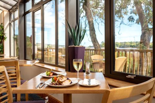 a table with a plate of food and a glass of wine at Passage House Hotel in Newton Abbot