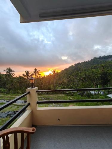 a balcony with a view of the sunset at Laras Homestay Munduk in Munduk