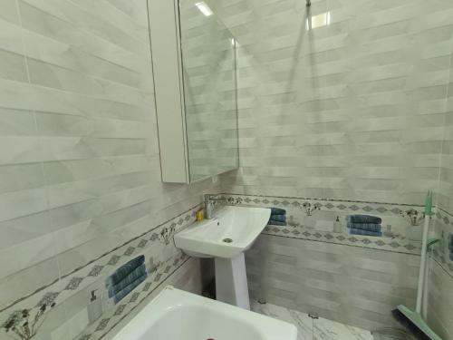 a white bathroom with a sink and a mirror at Квартира в тихом центре in Dushanbe