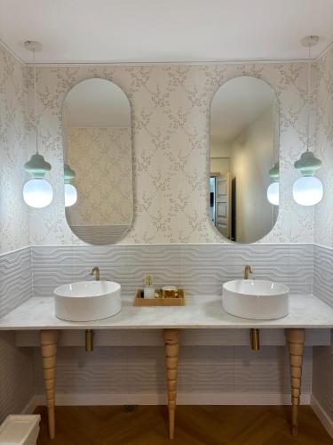 two sinks in a bathroom with two mirrors at Pensiunea agroturistica Elena in Drăgoiasa