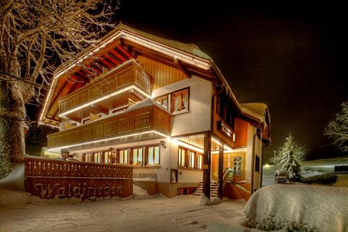 a house is lit up in the snow at night at derWaldfrieden naturparkhotel in Herrenschwand