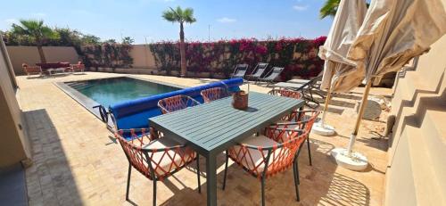 a table and chairs next to a swimming pool at Villa Saadia in Douar Bellouk