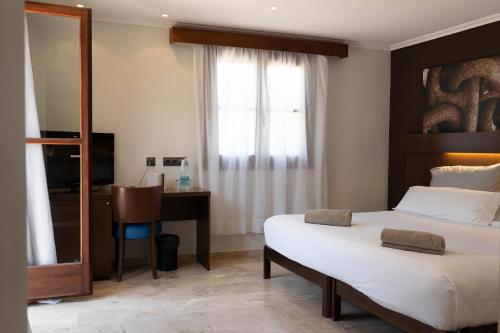 a bedroom with a bed and a desk and a mirror at Maristel Hotel & Spa - Adults Only in Estellencs