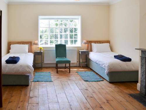 a room with two beds and a chair and a window at The Dower House in Stowbridge