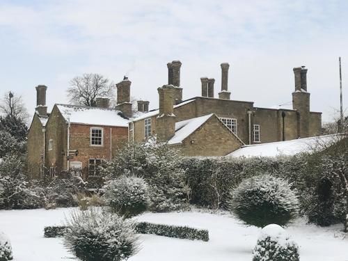an old brick house with chimneys in the snow at The Dower House in Stowbridge