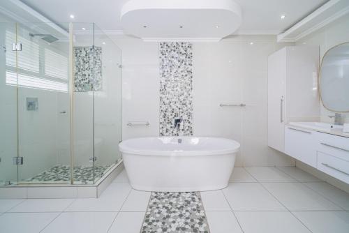 a white bathroom with a tub and a shower at 122 Camarque-Lavish lookout Penthouse in Umdloti