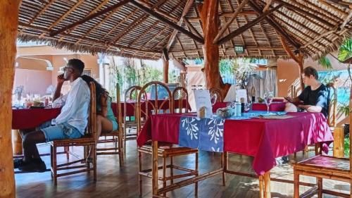 a group of people sitting at tables in a restaurant at Fleurs d'Ylang in Nosy Be