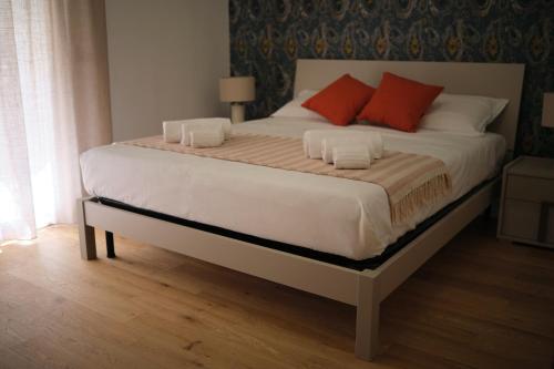 a bed with two red pillows on top of it at Gelone - Cairoli Apartments in Gela