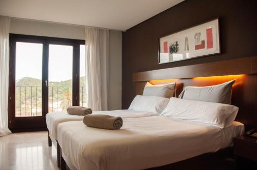 a bedroom with two beds with white sheets and a window at Maristel Hotel & Spa - Adults Only in Estellencs