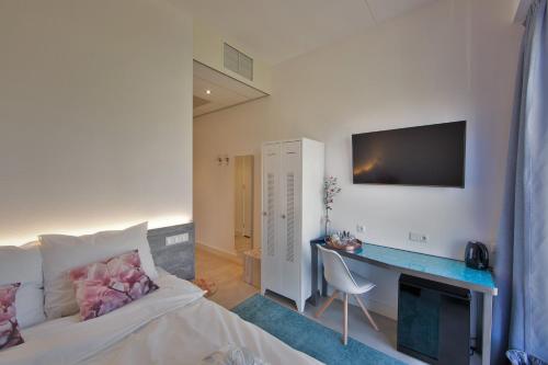 a bedroom with a bed and a desk with a television at Hotel Rauw aan de Kade in IJmuiden