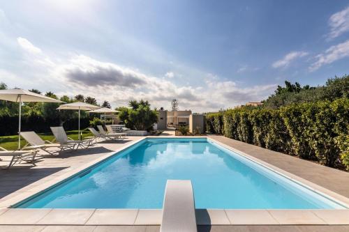 a swimming pool with chairs and umbrellas on a building at Villa Luisa in Noto Marina