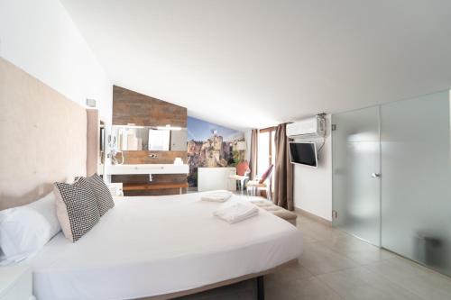 Un dormitorio con una gran cama blanca y una cocina. en Gav Espinel Ronda Centro, en Ronda