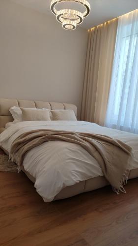 a bedroom with a large white bed with a chandelier at MONACO House in Chişinău
