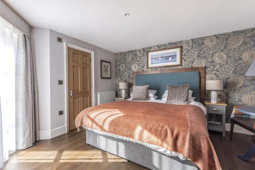 a bedroom with a bed and a wall with wallpaper at Cockhaven Arms in Bishopsteignton