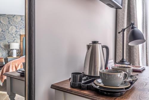 a table with a tea kettle and cups on it at Cockhaven Arms in Bishopsteignton