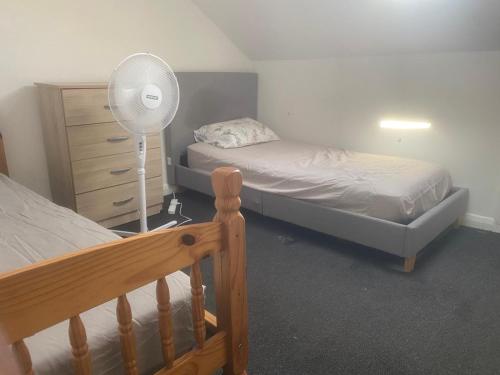 a bedroom with two beds and a fan and a dresser at The Haven Loft-Cozy Room in a house in Grays Thurrock
