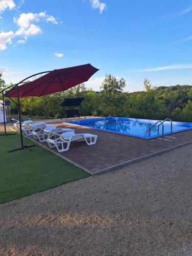 a pool with an umbrella and chairs and a table at Vikendica Hangover in Gradačac