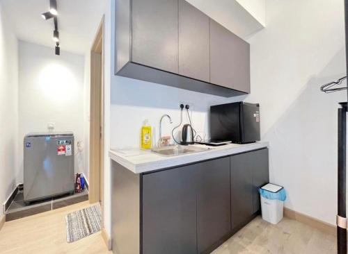 a small kitchen with a sink and a microwave at Luxe by KLCC in Gua Sai