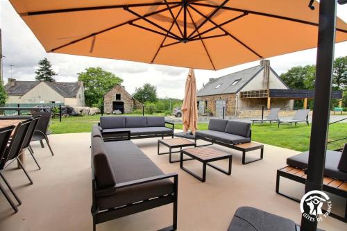 a patio with couches and tables and an umbrella at Gite de branfere in La Gacilly