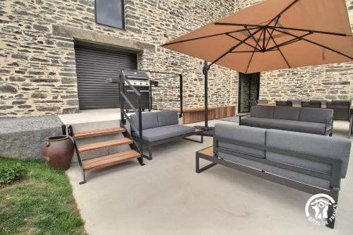 a patio with two benches and an umbrella at Gite de branfere in La Gacilly