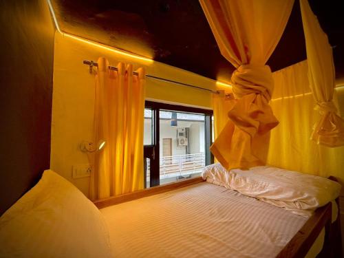 a bedroom with a bed with yellow curtains at Friends by Alizeh Bhagsunag McLeodganj in McLeod Ganj