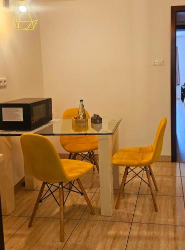 a dining room table with yellow chairs and a bottle on it at Szklane Domy in Zakopane