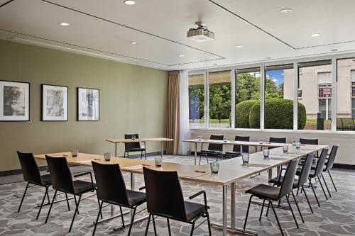 a conference room with tables and chairs and windows at Leonardo Hotel Mainz in Mainz