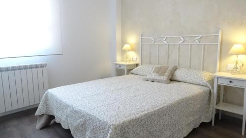 ein Schlafzimmer mit einem Bett, zwei Tischen und einem Fenster in der Unterkunft San Pedro in Teruel