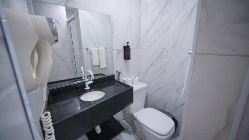 a white bathroom with a sink and a toilet at Davila Flat Hotel in Fortaleza