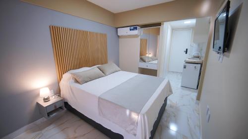 a small bedroom with a white bed and a television at Davila Flat Hotel in Fortaleza