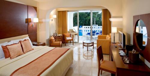 a hotel room with a bed and a living room at Grand Sunset Princess - All Inclusive in Playa del Carmen