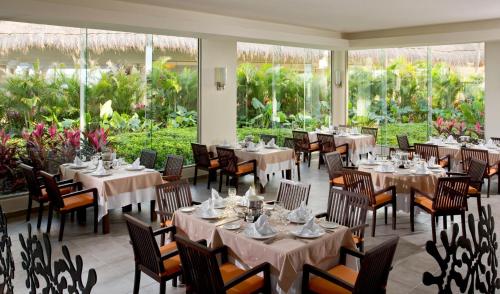 a dining room with tables and chairs and windows at Grand Sunset Princess - All Inclusive in Playa del Carmen