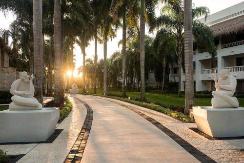 two statues sitting on a road with palm trees at Grand Sunset Princess - All Inclusive in Playa del Carmen