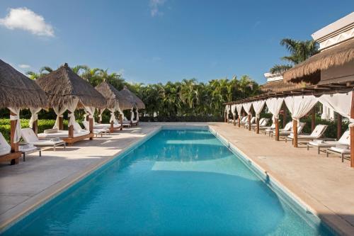 a pool at a resort with chairs and umbrellas at Grand Sunset Princess - All Inclusive in Playa del Carmen