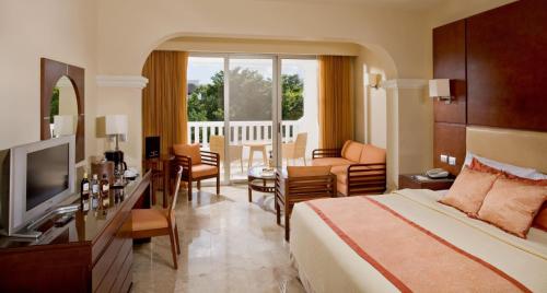 a hotel room with a bed and a living room at Grand Riviera Princess - All Inclusive in Playa del Carmen