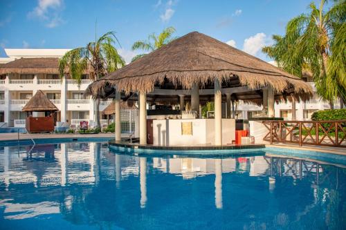 a resort swimming pool with a large thatch hut at Grand Riviera Princess - All Inclusive in Playa del Carmen