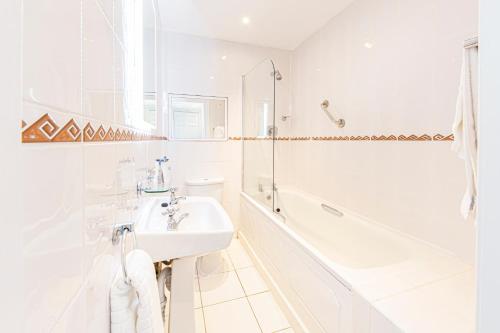 a white bathroom with a sink and a bath tub at The Beaches Hotel and Spa in Prestatyn