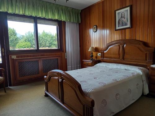 a bedroom with a large wooden bed and two windows at Casa Celia Camino Portugues in Tui