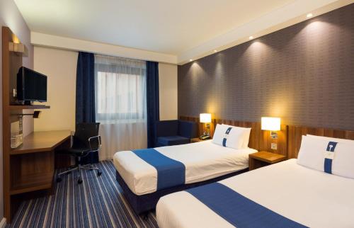 a hotel room with two beds and a desk at Holiday Inn Express Harlow by IHG in Harlow