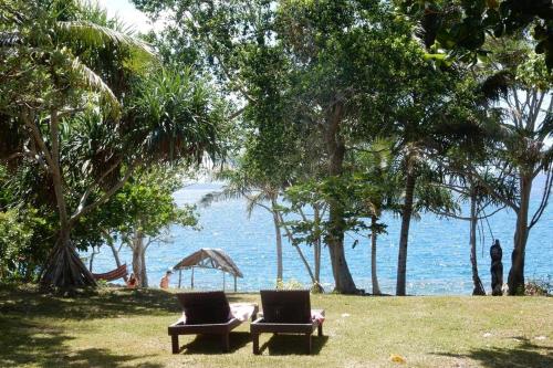 two chairs sitting on the grass near the water at Angels Beachhouse - Beachfront, fast internet, Queen beds, new owners in Port Vila