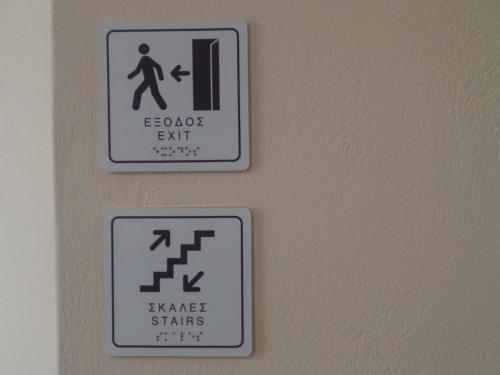 two signs on the wall of a bathroom at Galini Hotel in Skala Eresou