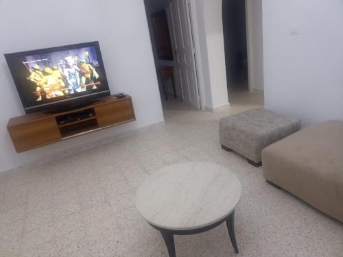a living room with a tv and a table and a stool at Appartment, séjour Djerba 2 in Arkou