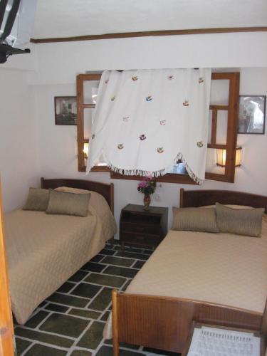 a bedroom with two beds and a curtain over the window at Pension Irini-Vicky in Ios Chora