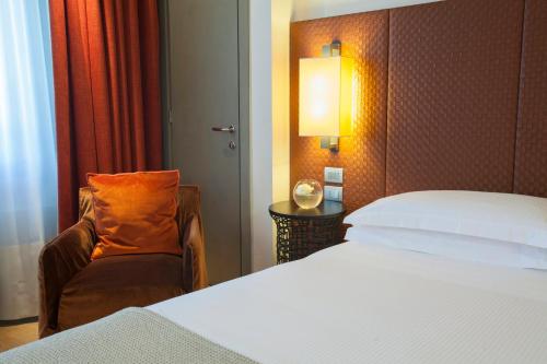 a hotel room with a bed and a chair at Starhotels Michelangelo Florence in Florence